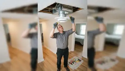 Electrician installing a whole-house fan ceiling unit and insulated damper in an Allentown, PA home